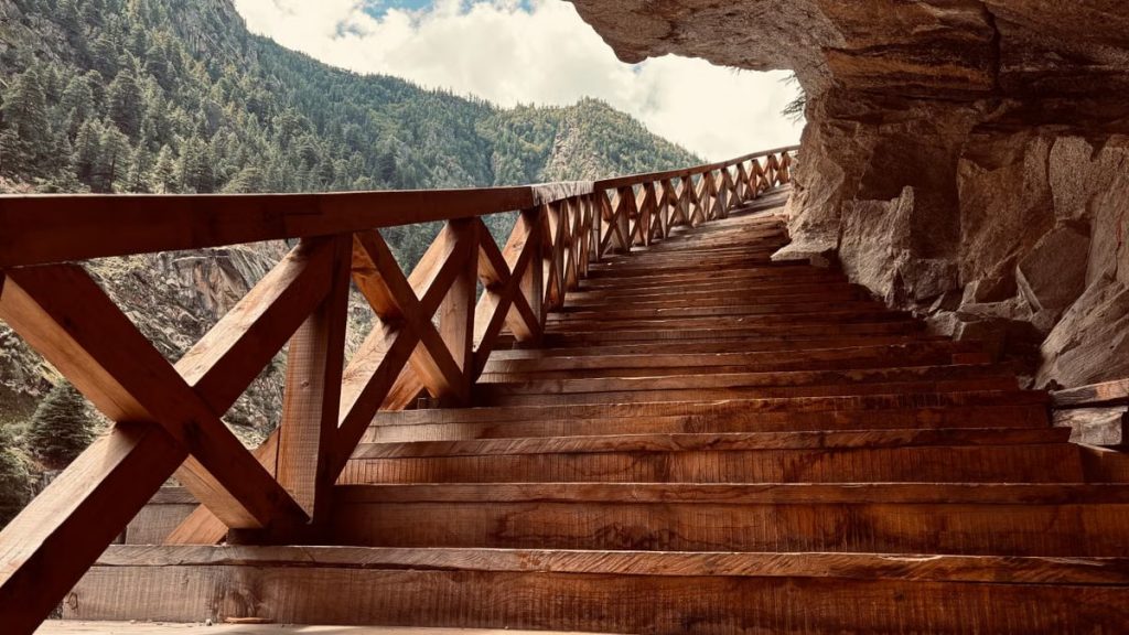 Scenic view of wooden stairs leading through a mountain passage in Bhatwari, showcasing nature's beauty.